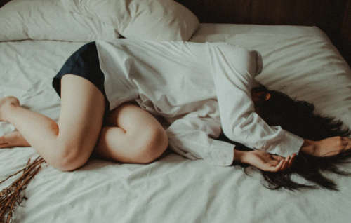 women lying depressed on bed