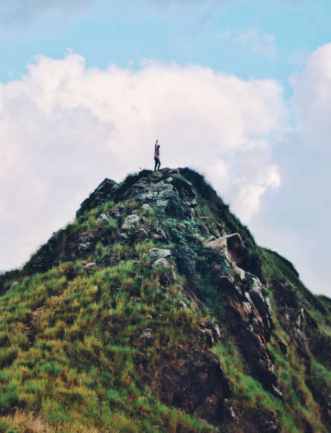 man on top of mountain with fist raised