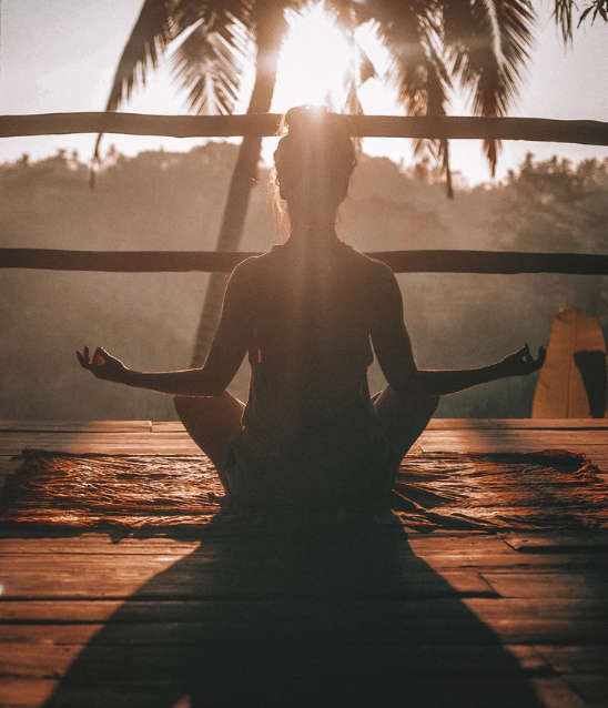 woman meditating at sunset
